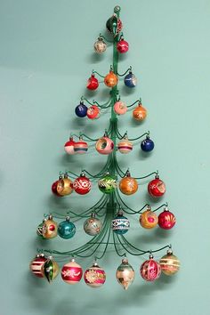 a small christmas tree with ornaments hanging from it's sides on a blue wall