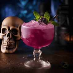 a pink drink with blackberries and mint garnish