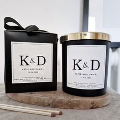 two candles sitting on top of a table next to a box with the initials k and d