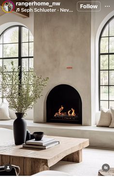 a living room filled with furniture and a fire place in front of two large windows