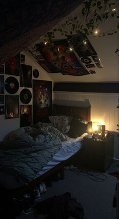 an unmade bed in a dimly lit room with pictures on the wall above it