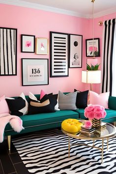 a living room with pink walls and black and white rugs on the floor next to a green couch