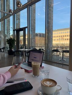 a woman sitting at a table with a laptop and cup of coffee in front of her