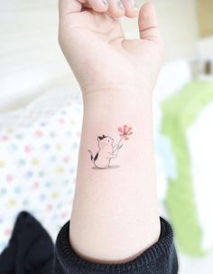 a person with a small tattoo on their wrist holding up a flower in the air