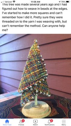 a christmas tree made out of beads on top of a wooden table next to a house