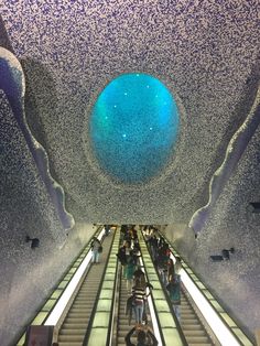 an escalator with people on it and a blue ball at the top in the middle