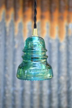 a green glass light hanging from a wire