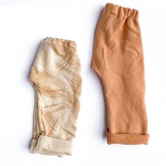 two pieces of cloth sitting next to each other on a white surface, one with an orange and beige design