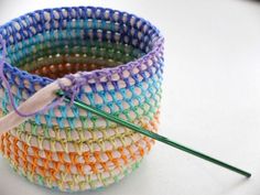 a crocheted basket with a knitting needle in it