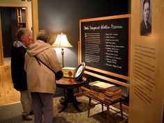 two people standing in front of a blackboard with writing on it and a lamp next to it