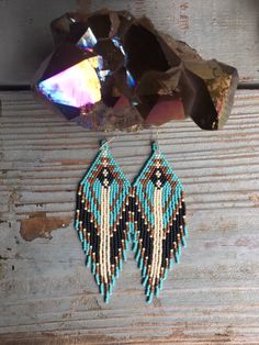 two pairs of beaded earrings hanging from a piece of wood