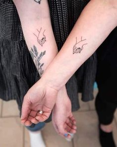 two people holding hands with tattoos on their arms and one is holding the other's hand