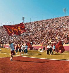 a group of people standing on top of a field holding red and yellow flags in front of a crowd