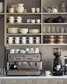 a coffee bar with lots of cups and saucers on the shelves above it,