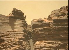 two large rocks sticking out of the side of a cliff face in an arid area