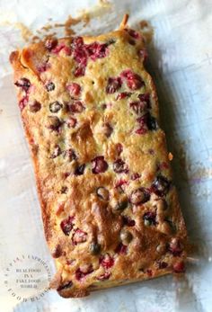 a piece of cake sitting on top of a white paper covered in cranberries