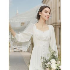 a woman in a white wedding dress holding a veil over her head and wearing a flower bouquet