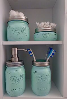 three mason jars with toothbrushes, soap and lotion in them on shelves