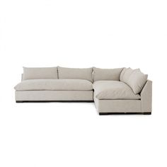 a large sectional couch with pillows on the top and bottom, sitting in front of a white