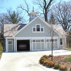 a car is parked in front of a two - story garage with an attached carport