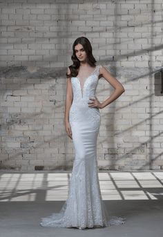 a woman in a white wedding dress standing next to a brick wall