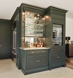 a kitchen with green cabinets and shelves filled with glasses on the top shelf, next to stairs