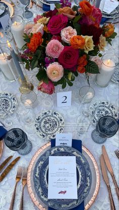 the table is set with plates, silverware, and candles for an elegant dinner