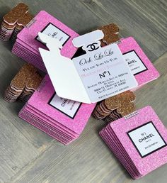 pink and gold glittered wedding favors with tags on the top are sitting on a wooden table