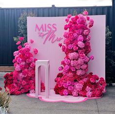 pink flowers are growing on the side of a building with a sign that says miss me