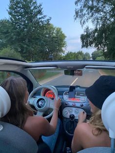 two women are driving down the road in a car with their hands on the steering wheel