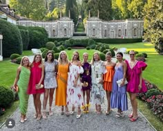 a group of women standing next to each other in front of a lush green field