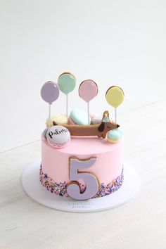 a pink birthday cake with lots of colorful candies on top