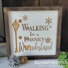 a wooden frame with the words walking in a disney wonderland on it next to pine cones