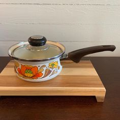 a pot with a lid sitting on top of a wooden board