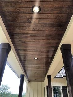 an outdoor covered porch with lights on the ceiling and wood columns in front of it