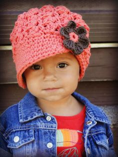 a small child wearing a crocheted hat with a flower on it's side