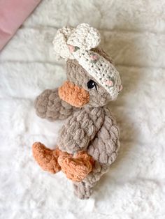 a crocheted teddy bear sitting on top of a white blanket