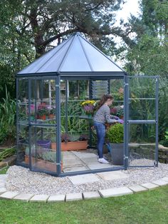 a woman standing in a greenhouse with potted plants