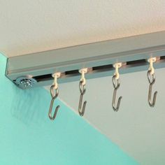 several hooks are hanging on the side of a blue and white wall next to a pair of scissors