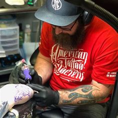 a man getting his tattoo done by another person in a room with lots of other items