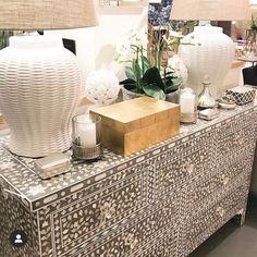 two white vases sitting on top of a table next to lamps and other items