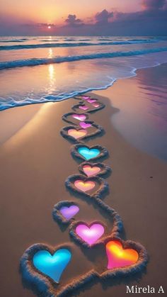 hearts are lined up on the beach at sunset