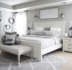 a white bed sitting in a bedroom on top of a carpeted floor next to a window