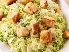 a white plate topped with shaved brussels sprouts and tofu cubed croutons