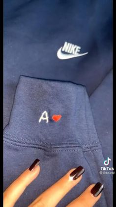 a woman's hand with black and white nail polish holding onto a nike sweatshirt