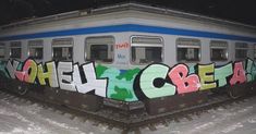 a train covered in graffiti sitting next to a snow covered platform with the word berlin painted on it