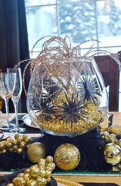 the table is set with gold and black ornaments, wine glasses, and candlesticks