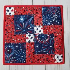 a red, white and blue quilted placemat with stars in the center on a wooden surface