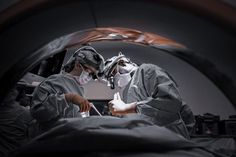 two surgeons performing surgery in an inclosure with the help of their surgical equipment