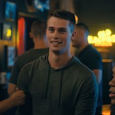 two young men standing next to each other in a room with neon signs on the walls